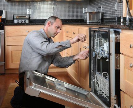 Мастер осматривает посудомоечную машину
